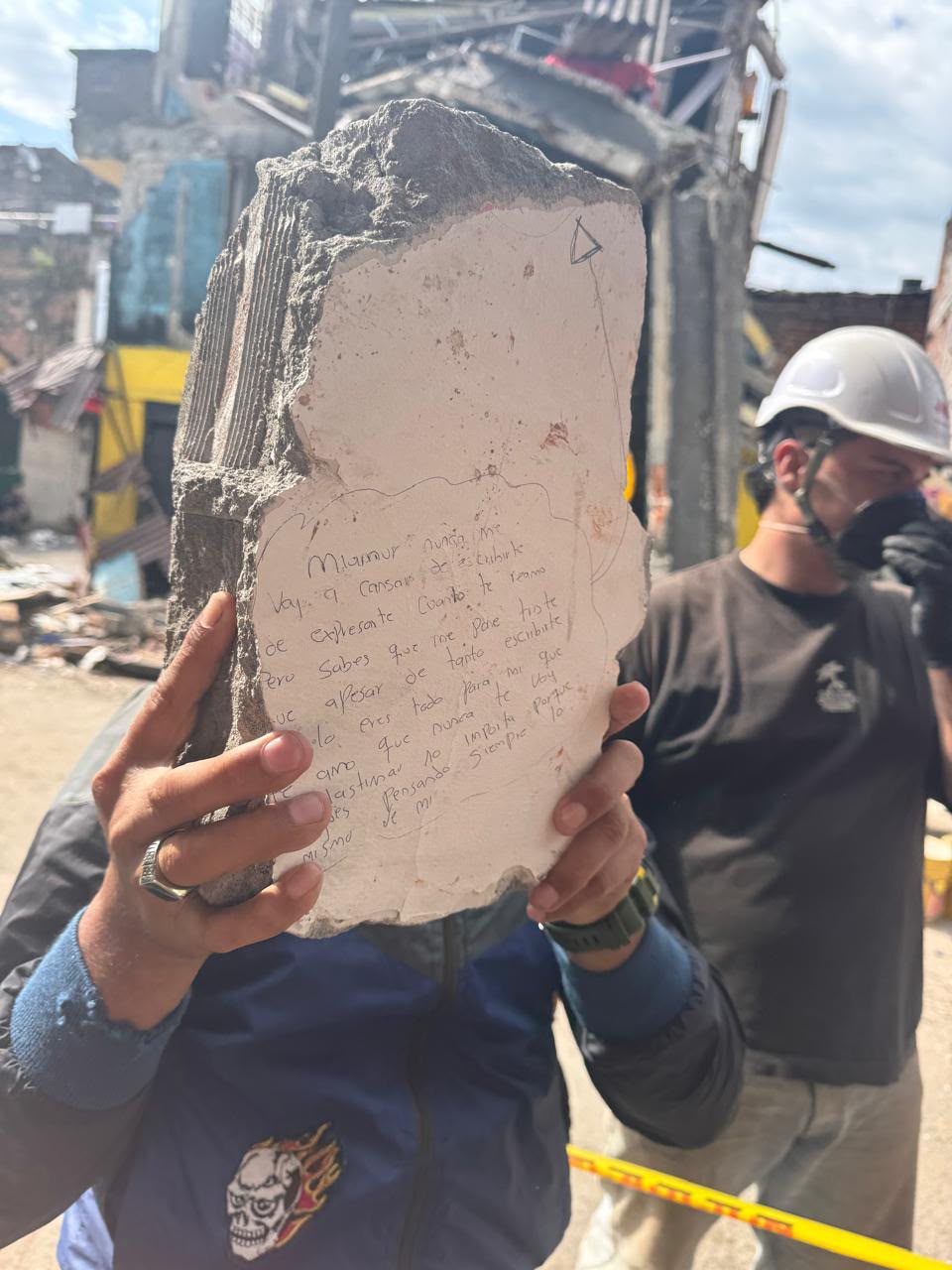 Un voluntario sostiene un fragmento de pared rescatado de los escombros con una carta de amor escrita a mano